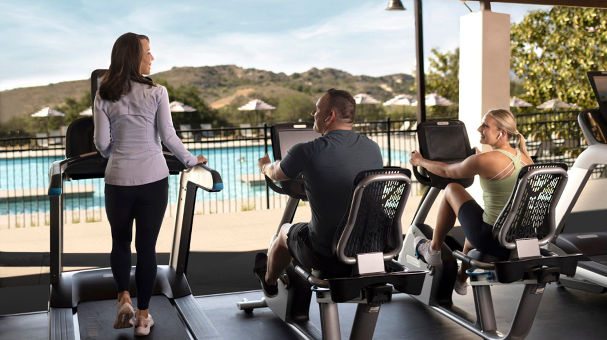 people on exercise equipment overlooking the pool